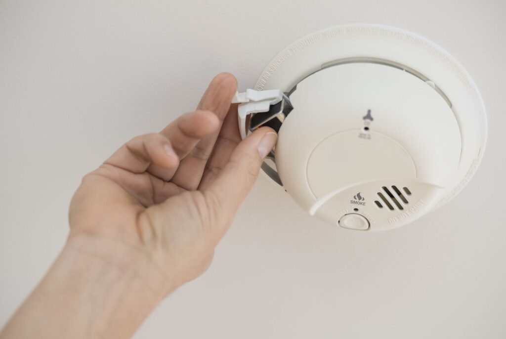 How do I safely turn off power and handle old detectors when replacing hardwired smoke detectors